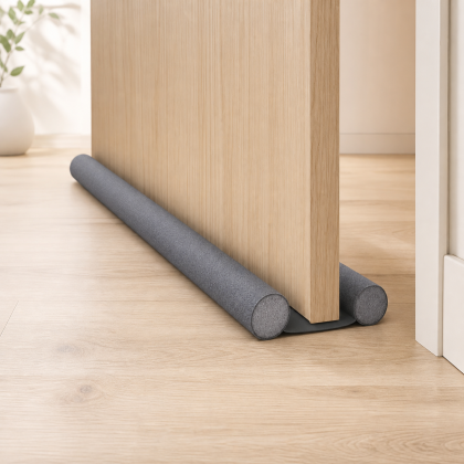 Double-sided gray foam door draft blocker installed under a door
